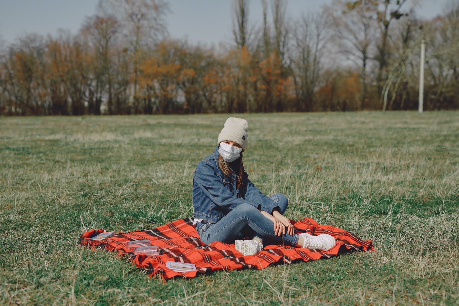 young girl in face mask resting on plaid in park