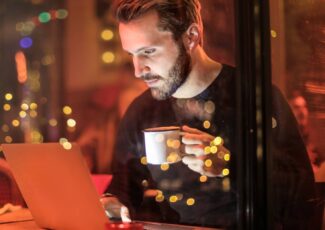 man holding mug in front of laptop