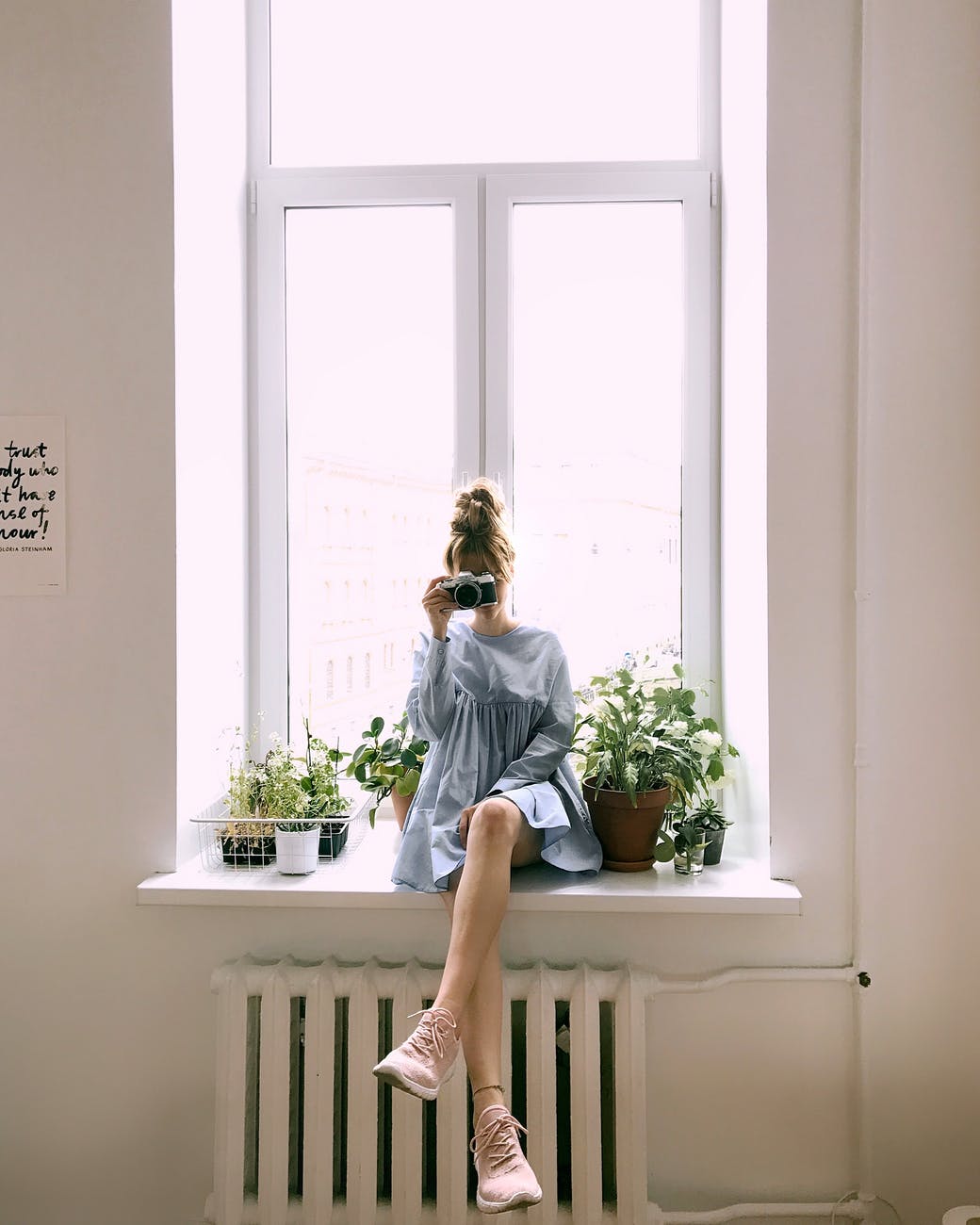woman in grey long sleeved dress sitting on window