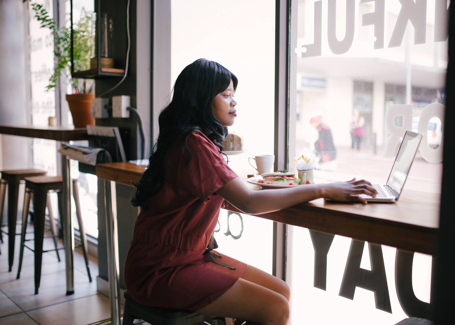 woman in red dress using laptop on table