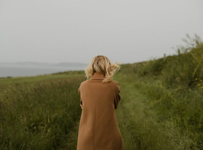 anonymous woman walking in cold field